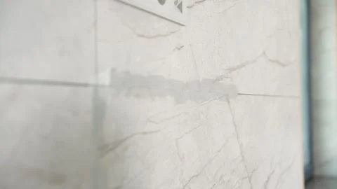 Hand applying grout between marble tiles during bathroom renovation Stock Footage 340458679