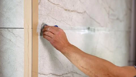 Hand applying grout to marble tile wall with blue tool Stock Photos