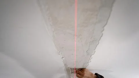 Hand applying plaster with red laser guide on ceiling corner Stock Photos