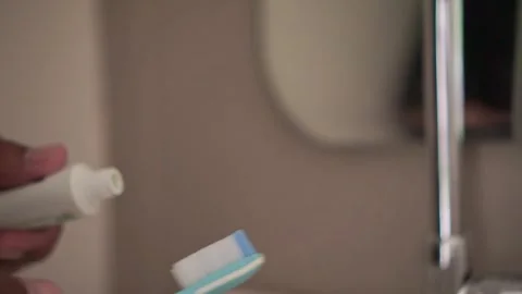 Hand applying toothpaste to a toothbrush before brushing teeth. Vídeos de archivo 338191165