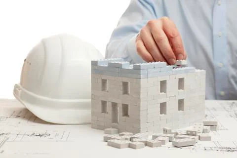 Hand of an architect constructing a house with toy blocks - white background Фото