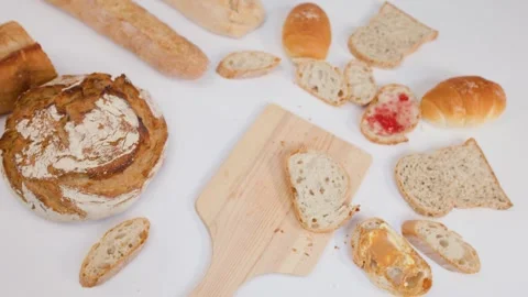 Hand Arranging Fresh Sourdough Bread and Butter on White Background Vídeos de archivo 337224971