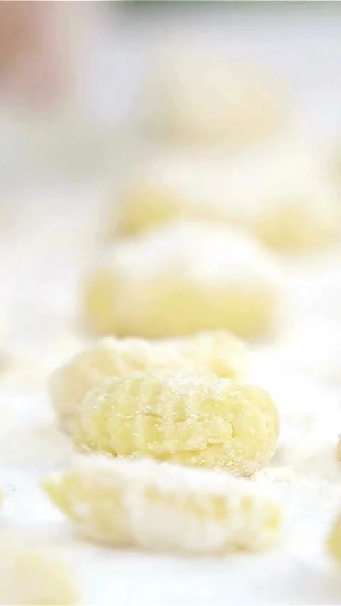 Hand arranging raw potato gnocchi on floured white surface Video stock 334169138