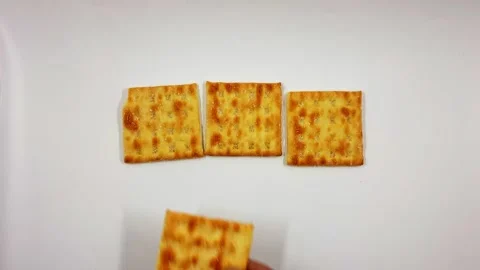 Hand arranging square crackers on a white surface for a snack display Stock Footage 322511896