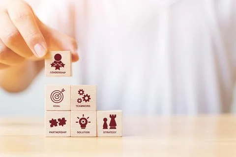 Hand arranging wood block stacking with icon leader business. Key success fac Fotos de archivo