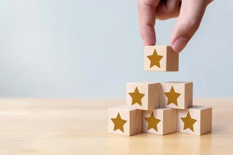 Hand arranging wood block stacking as step stair with five star shape. The be Stock Photos