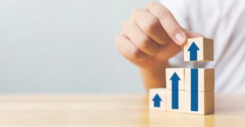 Hand arranging wood block stacking as step stair with arrow up. Ladder career Stock Photos