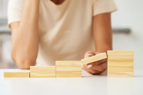 Hand arranging wood cube stacking as stair step shape Stock Photos
