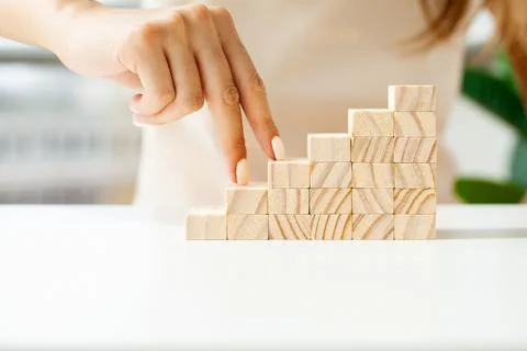 Hand arranging wood cube stacking as stair step shape Stock Photos