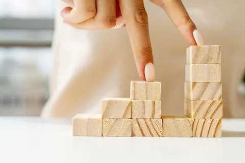 Hand arranging wood cube stacking as stair step shape Foto stock