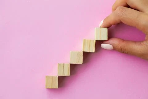Hand arranging wood cube stacking as step stair. Stock Photos