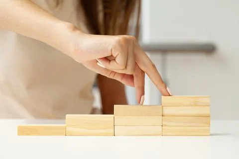 Hand arranging wood cube stacking as step stair. Stock Photos