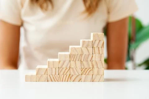 Hand arranging wood cube stacking as step stair. Stock Photos