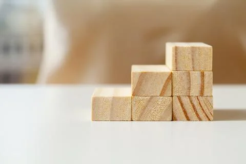 Hand arranging wood cube stacking as step stair. Stock Photos