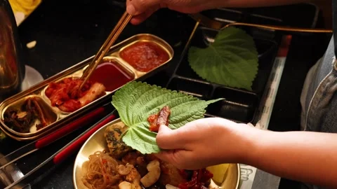 Hand Assembles Pork and Kimchi Wrap at Korean BBQ Table Stock Footage 318442232