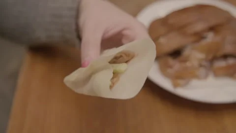 Hand Assembling Pancake Wrap with Sliced Meat and Vegetables in Beijing Stock Footage 345766402