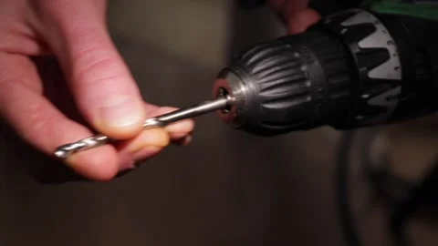Hand attaching a metal drill bit into the chuck of a cordless power screwdr.. Stock Footage 320738440