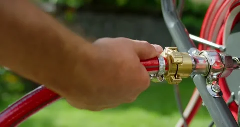 Hand Attaching a Red Garden Hose to a Hose Cart in the Garden Vídeo Stock 340294978