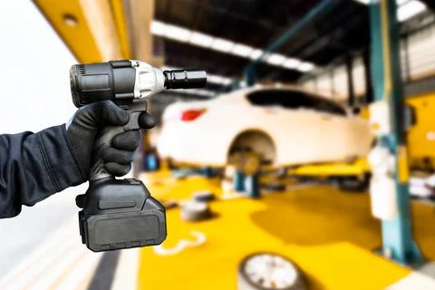 Hand of an auto mechanic using a cordless impact wrench in a car repair facility Foto stock