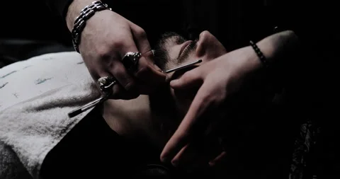 Hand of barber keeping straight razor and cutting trendy stripes on beard Stock Footage 150272011