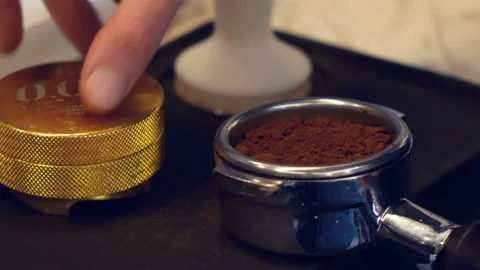 Hand of barista using tamper to press ground coffee into portafilter to make Video stock 100401756
