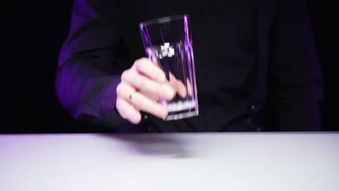 Hand of bartender in black uniform puts transparent glass on white background Stock Footage 168944977