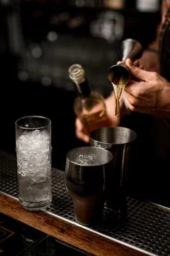 Hand of bartender masterfully pours drink from jigger into steel shaker glass Stock-Fotos