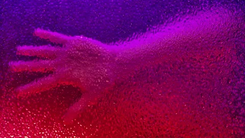 Hand behind textured glass with dramatic colored lighting Video stock 313539947