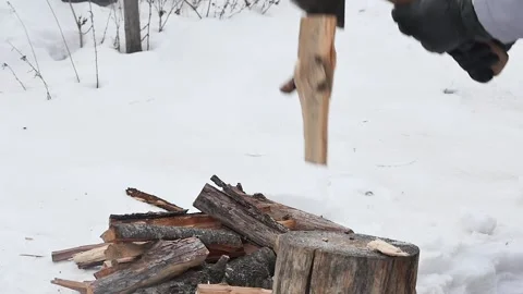 A hand in a black glove with an ax cannot cut a log in a snowy yard, slow mo 動画素材 234474887