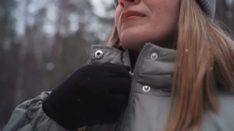 Hand in black glove pulling zipper on gray winter coat in snowy outdoor setting Stock Footage 318242431