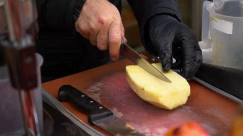 Hand in black gloves cutting pineapple on a chopping board at street Stock Footage 264553198