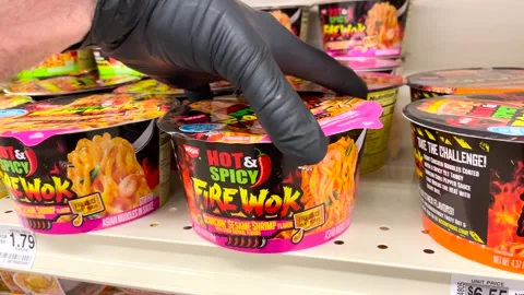 A hand with black gloves pick up Hot and Spicy ramen bowl retail store shelf Stock Footage 175530198