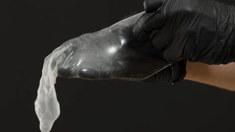 A Hand in Black Gloves Pulling a Condom Over the Entire Hand, Demonstrating Stock Footage 301083993