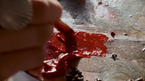 Hand Blending Glossy Red Paint with Brush on Artist Palette Stock Footage 322019684