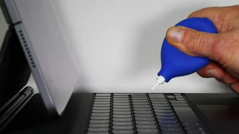 Hand blowing dust from a portable computer keyboard. Video stock 228445045