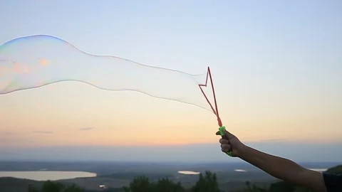 Hand blowing soap bubbles against the sunset sky Video stock 145630530
