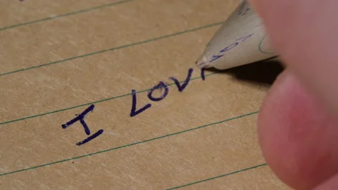 Hand with blue ballpoint pen writes I love you on Notebook, Macro Shot Stock Footage 235659519