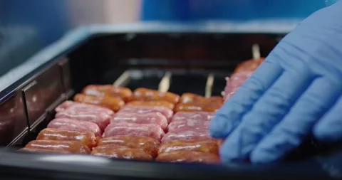 Hand in blue glove arranging raw marinated meat skewer in a black plastic tray Vídeo Stock 339962888