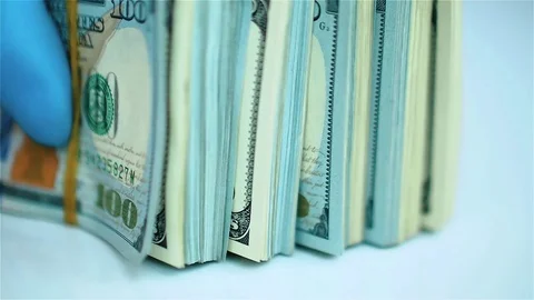 Hand in blue glove leafs through stack of US dollars. Close up view Stock Footage 72146376