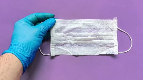 Hand with blue glove reaching protective surgical mask Stock Footage 130331395