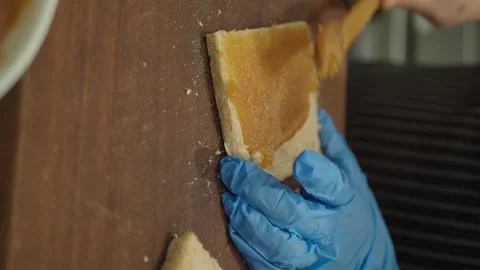Hand in blue glove spreading jam on slice of bread on wooden board. Stock Footage 332914683