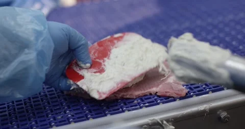 Hand in blue glove spreading light cream filling onto a thin slice of meat on a Vídeo Stock 339997305