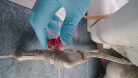Hand in Blue Glove Turning Red Ball Valve on Water Pipe | Plumber Shutting Off Stock Footage 341366301