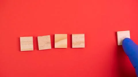 Hand in blue gloves point on clean wooden blocks on colored red background. M Stock Photos