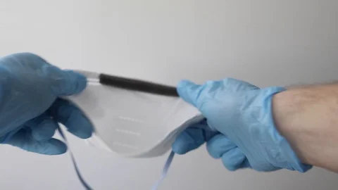 Hand in blue nitrile gloves holding mask sharing protective respirator. Stock Footage 127218641