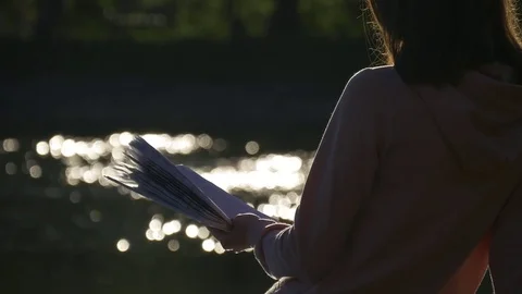 Hand with a book on the background of shiny water Stock Footage 75993595