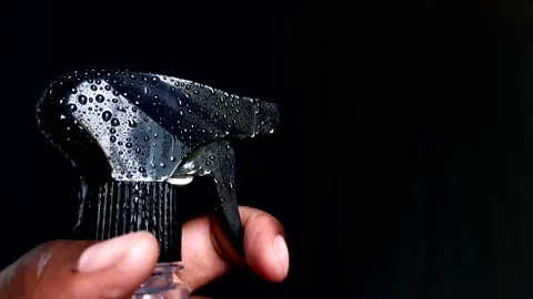 Hand with a bottle on a black background spraying liquid Stock Footage 200917384