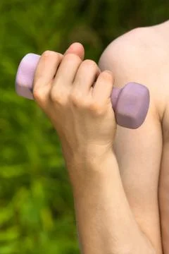 Hand of boy doing exercises with dumbbell on nature background Stock Photos