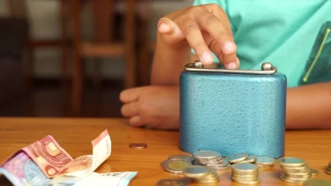 Hand of a boy saving money, putting coins in the vintage metal bank. Saving c Stock Footage 135968009