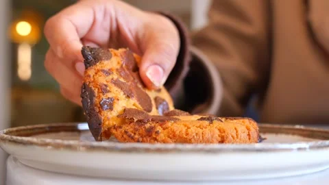 Hand breaking chocolate chip cookie in half over plate delicious dessert mo.. Stock Footage 332889295